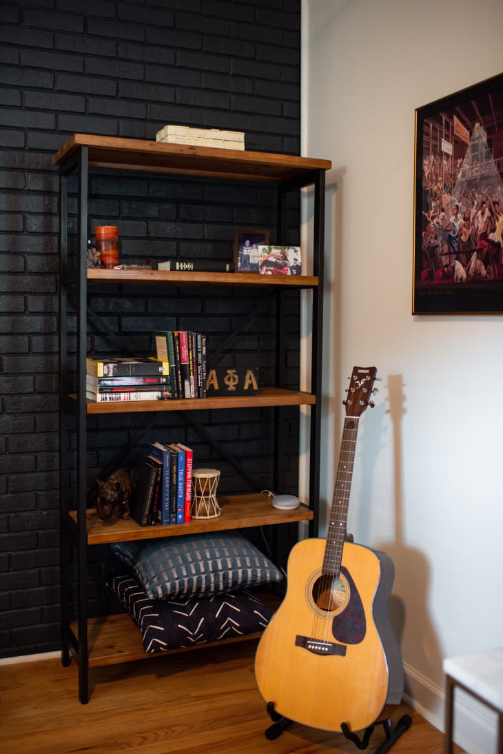 Corner of home with bookshelf and guitar.