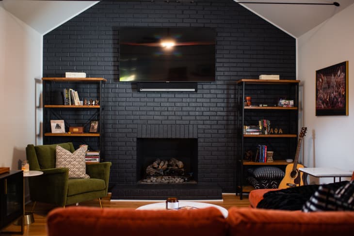 Dark colored brick wall in living room accented with pops of warm color.