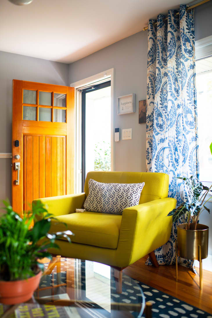 Wooden door opened in living room with bright yellow arm chair.
