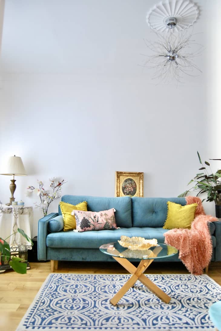 Jewel toned room with blue green sofa, yellow and pink pillows and a coral colored throw.