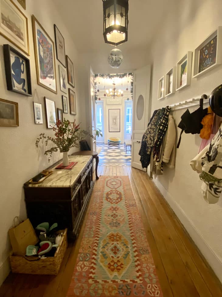 A hallway with framed photos on the walls and coats hanging from hooks