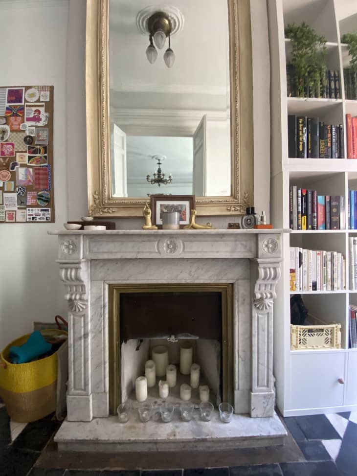 A white marble fireplace with a large mirror above