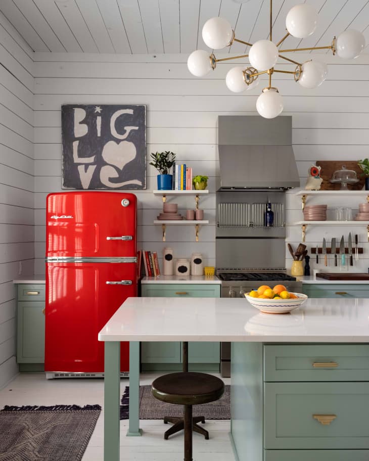 A kitchen with a red refrigerator and white walls