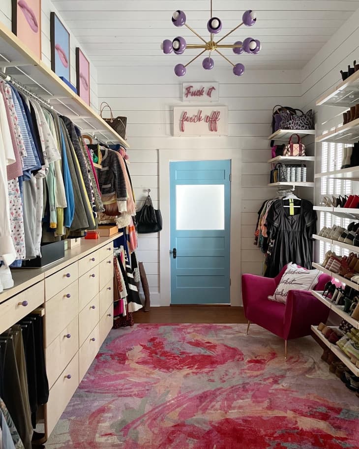 A closet with clothes hanging and white drawers below
