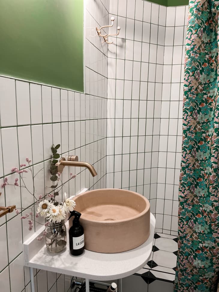 A bathroom with white tiled walls and a floral shower curtain
