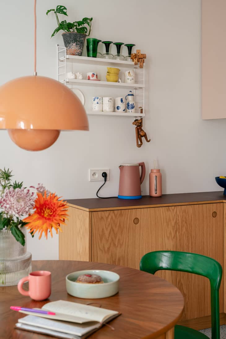 Colorful electric kettle on top of credenza off the side of a small dining room.