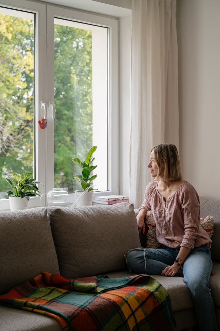 Homeowner, Kalina Juchnevic sitting on living room sofa looking out window.