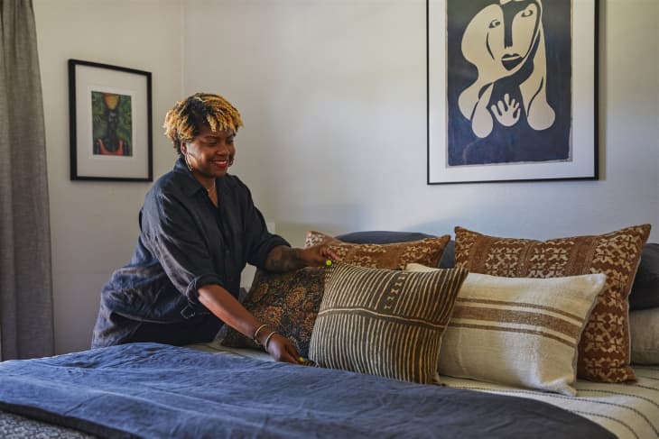 Latoya Skinner fluffing pillows in bedroom.