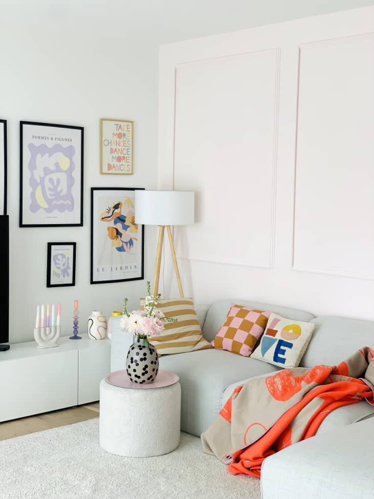 bright, airy, orange throw, pastel art, throw pillows, light blue couch, low couch, wainscoting, tri leg floor lamp