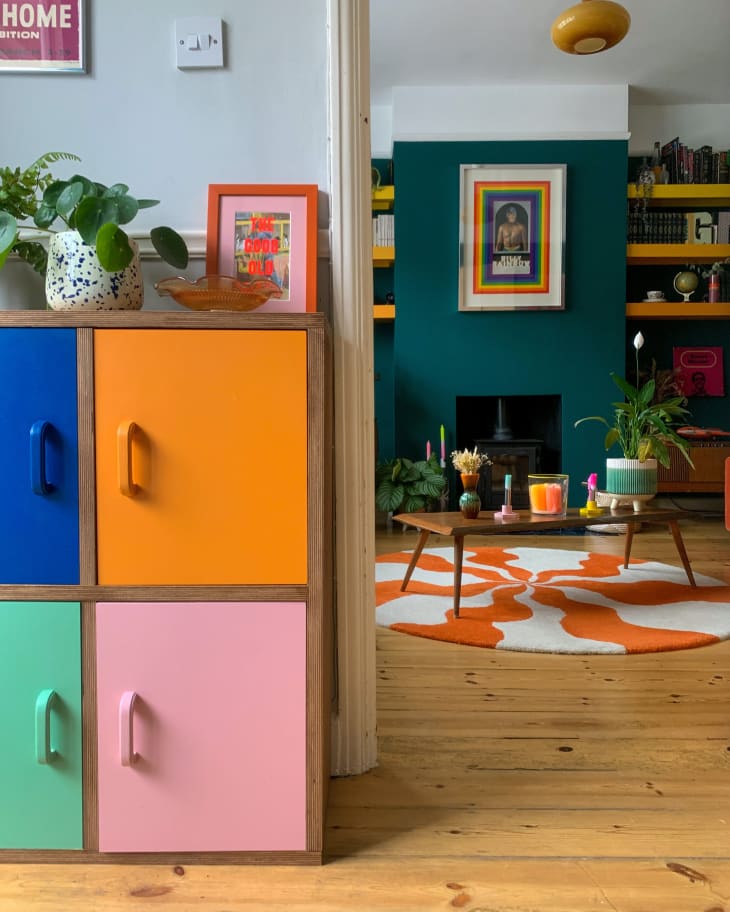 colorful cabinets, door frame, entry way, plants, orange and white wavey stripe rug, teal wall, coffee table, wood floors, natural light