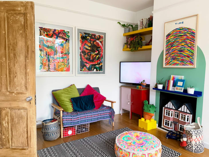 color block mural, green, colorful floor cushion, multi colored art, striped fabric bench, tv, toys, plants, yellow floating shelves, natural wood door