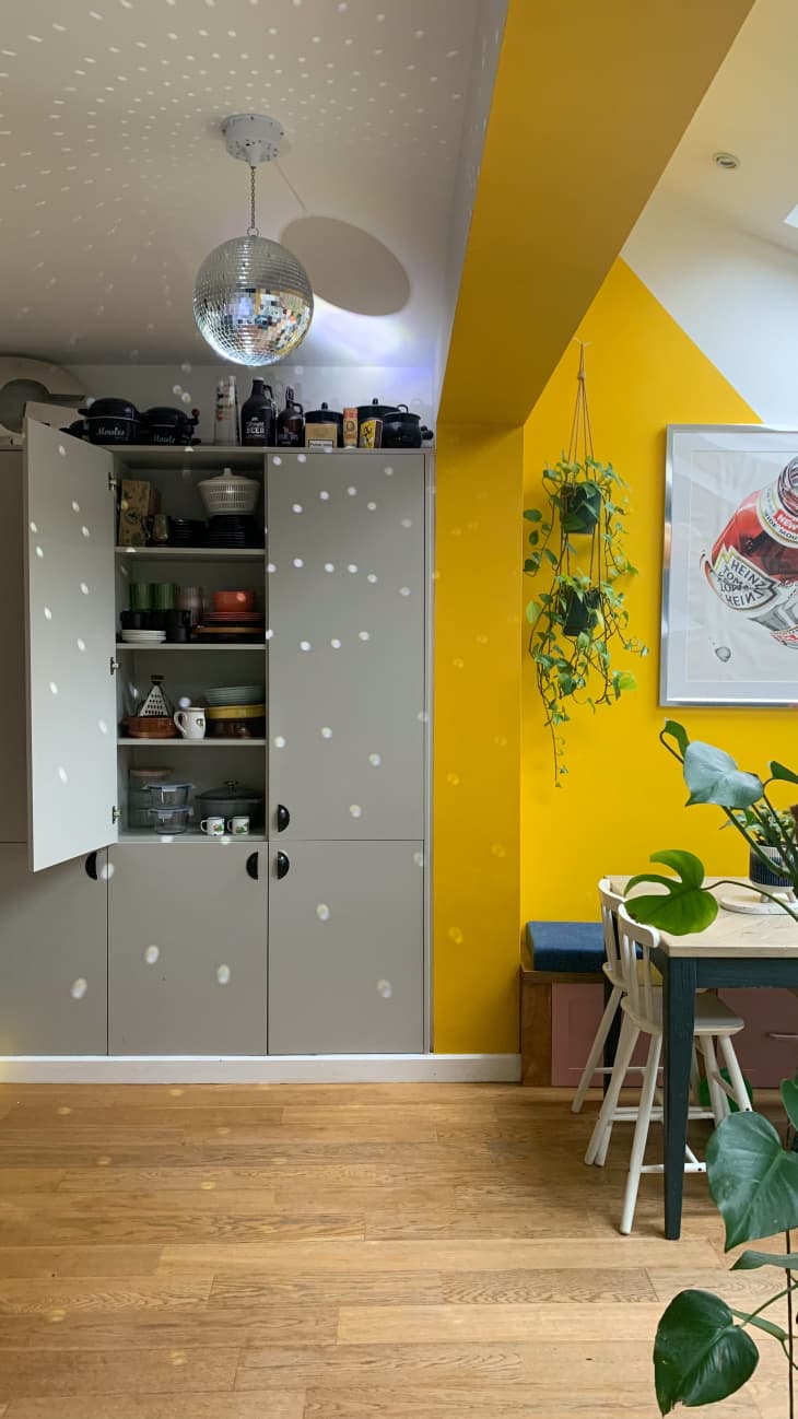 disco ball, hard wood floors, color blocking, yellow beam, grey built in cabinets, pantry, plants, table