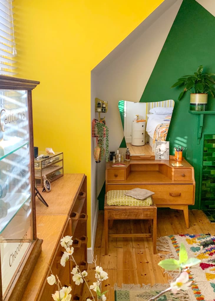 yellow color blocked wall, angled wall, green color blocking, natural wood vanity, glass display cabinet, natural wood dresser, wood floors, plants