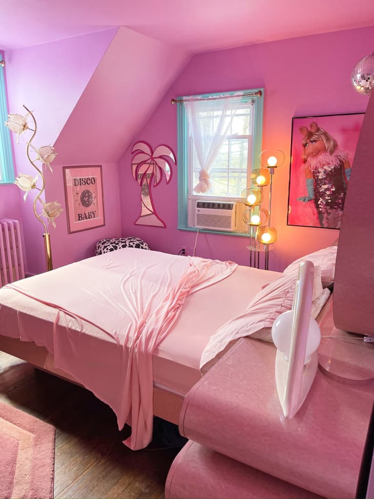 bedroom, hot pink, carousal horse, neon cowgirl light, vintage pink nightstand, vintage mirrir headboard, miss piggy art, disco ball, palm tree mirror art, angled wall, vintage lamps, wood floors, pink ceiling