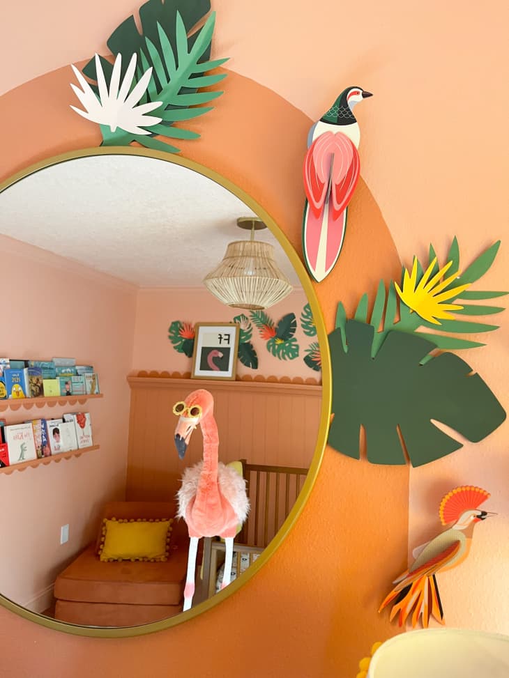 A circular mirror with orange and tropical accents in a nursery.