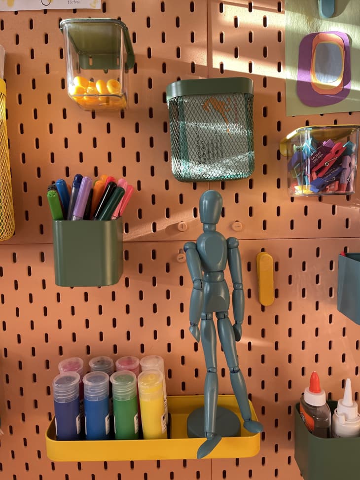 A pegboard hanging various art supplies in a playroom