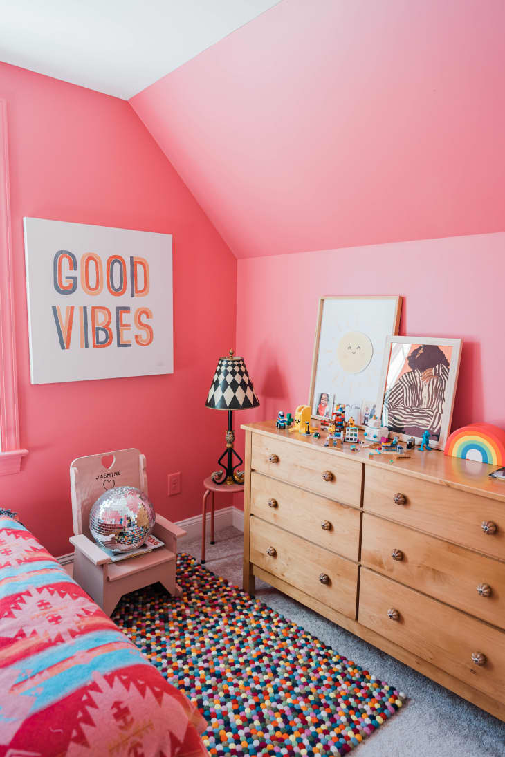 bedroom, pink walls, angled ceiling, good vibes, wood dresser, pok-a dot rug, child's chair, knickknacks