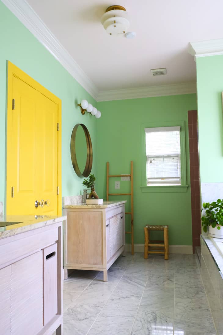 yellow door, green walls, glossy tile, tub, double vanity, crown molding, bathroom, plants