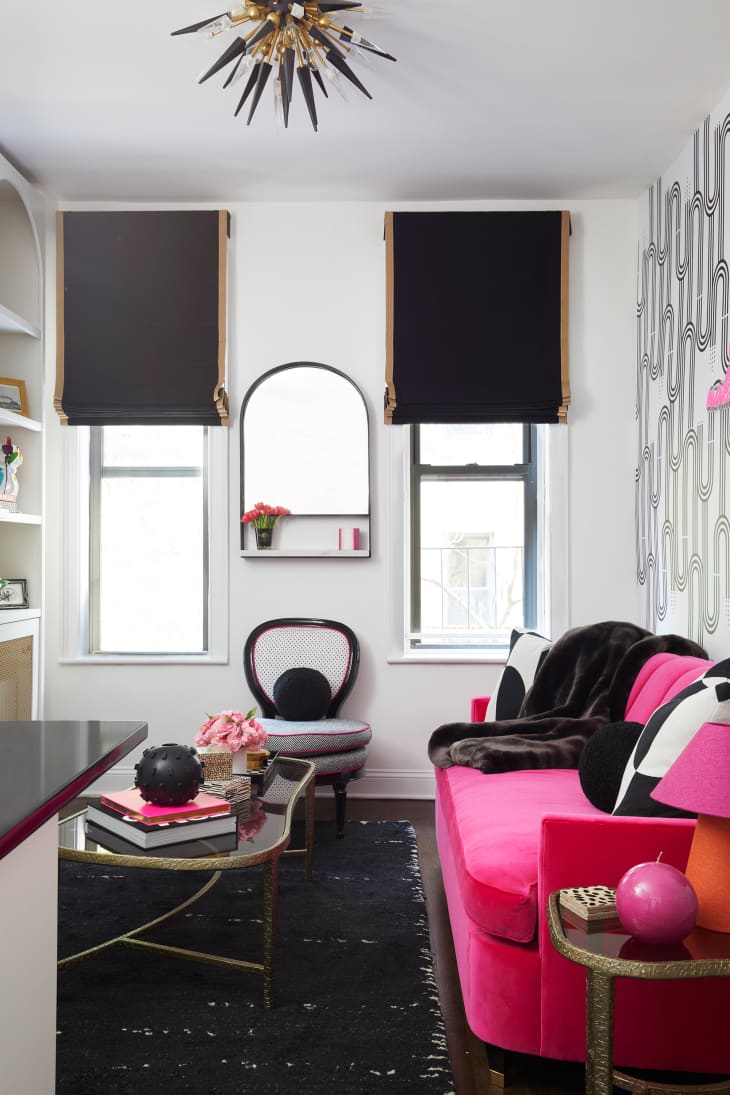 View into newly renovated living room with black and white graphic wall paper, bright pink sofa and other black and white accents throughout.