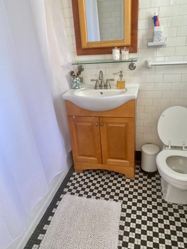 Checkerboard tile flooring in mid century bathroom with wooden vanity.