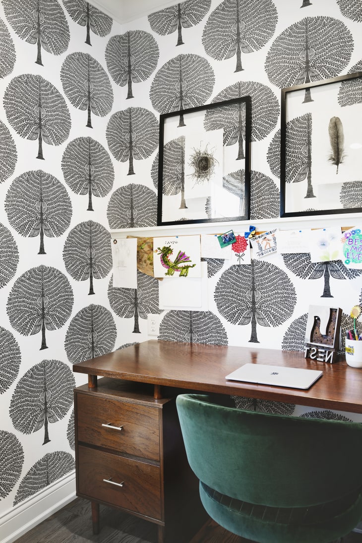 home office/workspace with black and white leaf fan wallpaper, wood desk, green velvet chair
