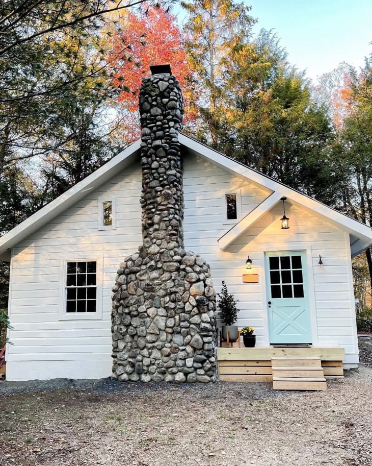 Exterior of cabin with stone chimney. Light blue door.