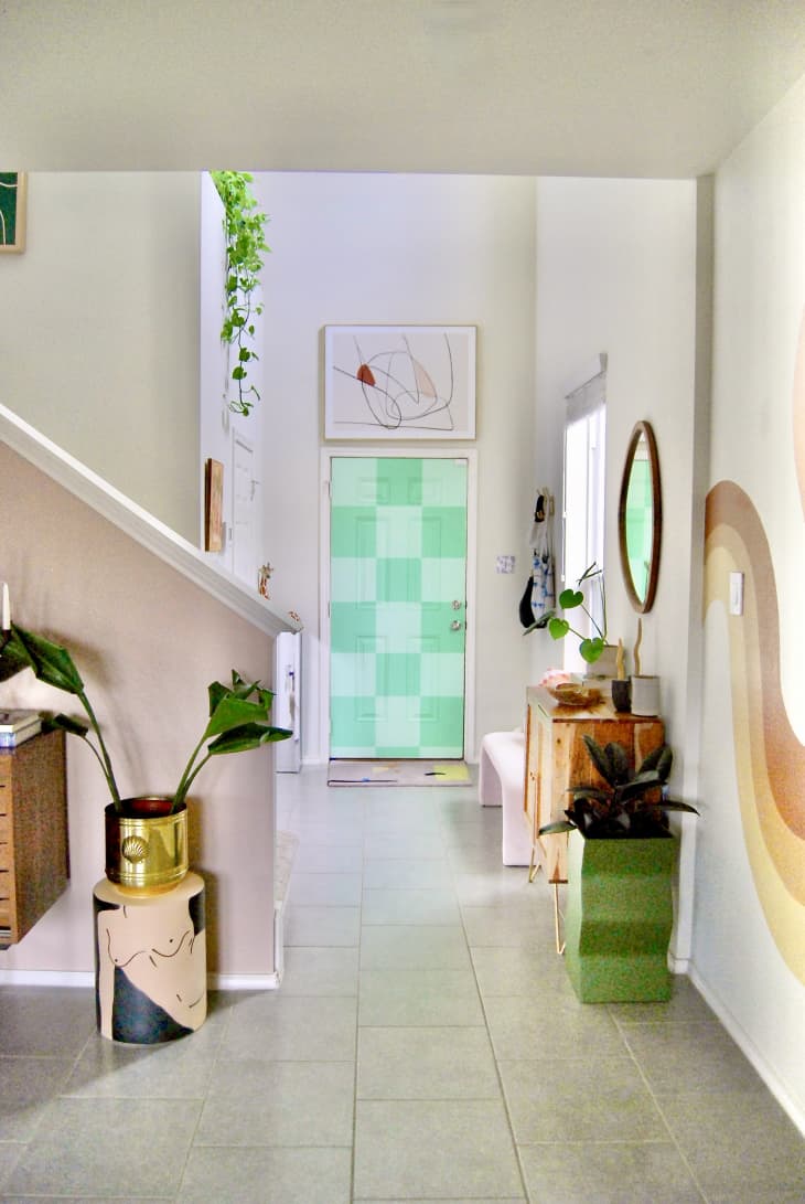 Colorful entryway with monochromatic checkerboard painted door. Abstract artwork above entry door.