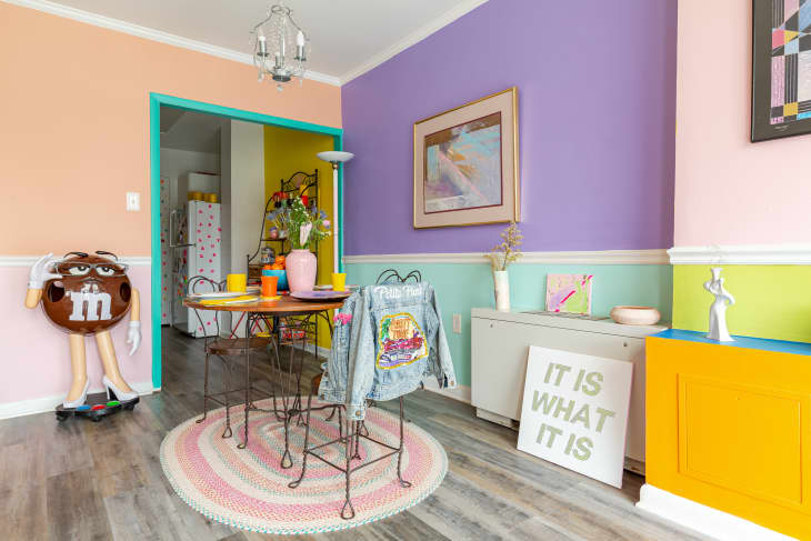 Dining room with lyrical iron chairs, walls painted in color blocks of chartreuse, pale aqua, lavender, pale pink, round pastel rug, multiple vases