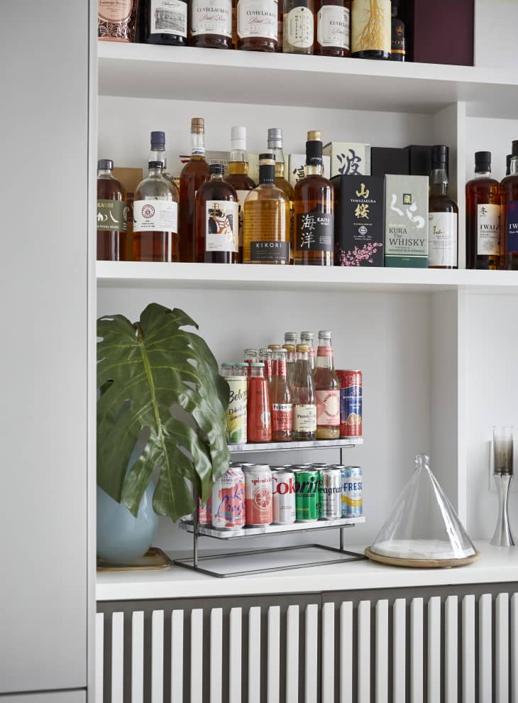 Detail of top of cabinet used as bar area with drinks, shelves above with liquor