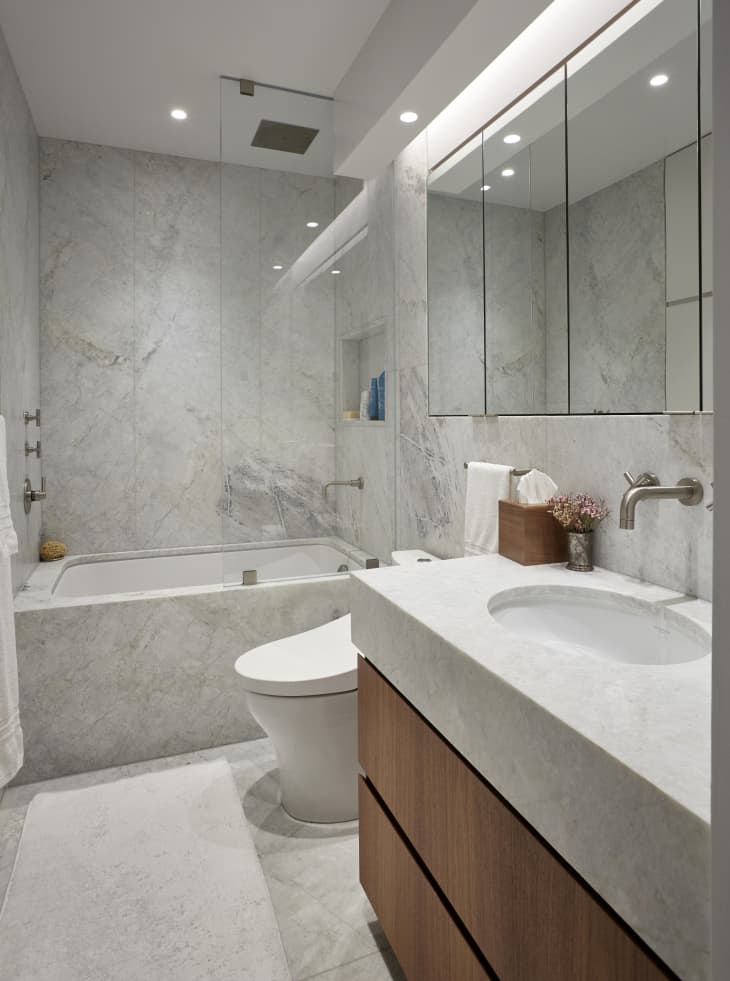 Bathroom with marble bath, wood cabinets with marble sink, modern design