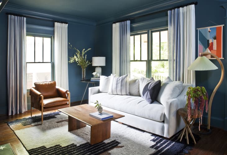 Living room after makeover with blue walls, white sofa, wood and warm-colored accents