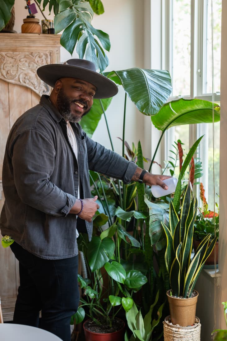 man tending to his houseplants by a window