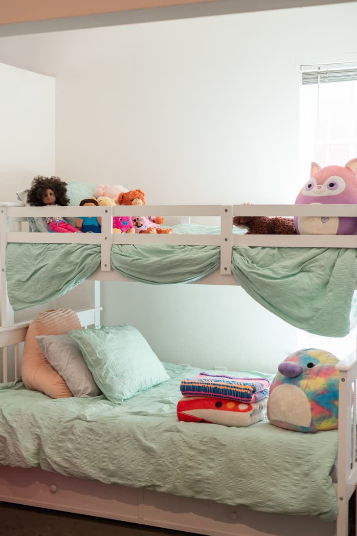kids' bunk bed with mint green bedding, stuffed toys, pillows