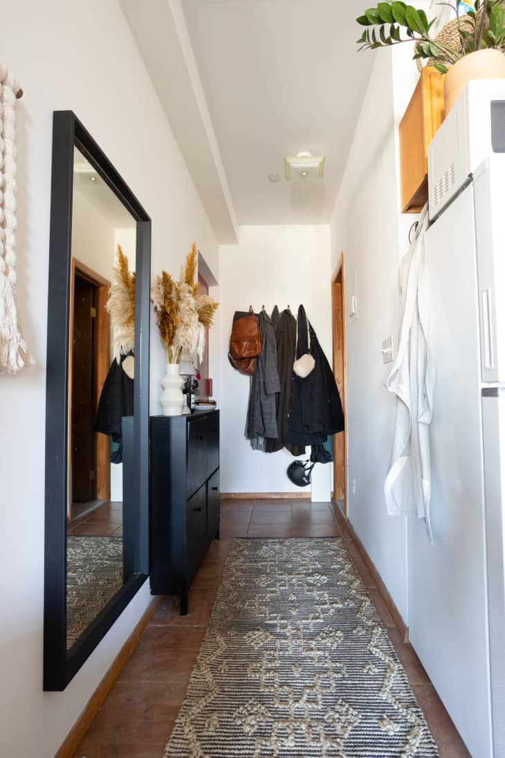 Coats hung at the end of the entry hallway in studio apartment.