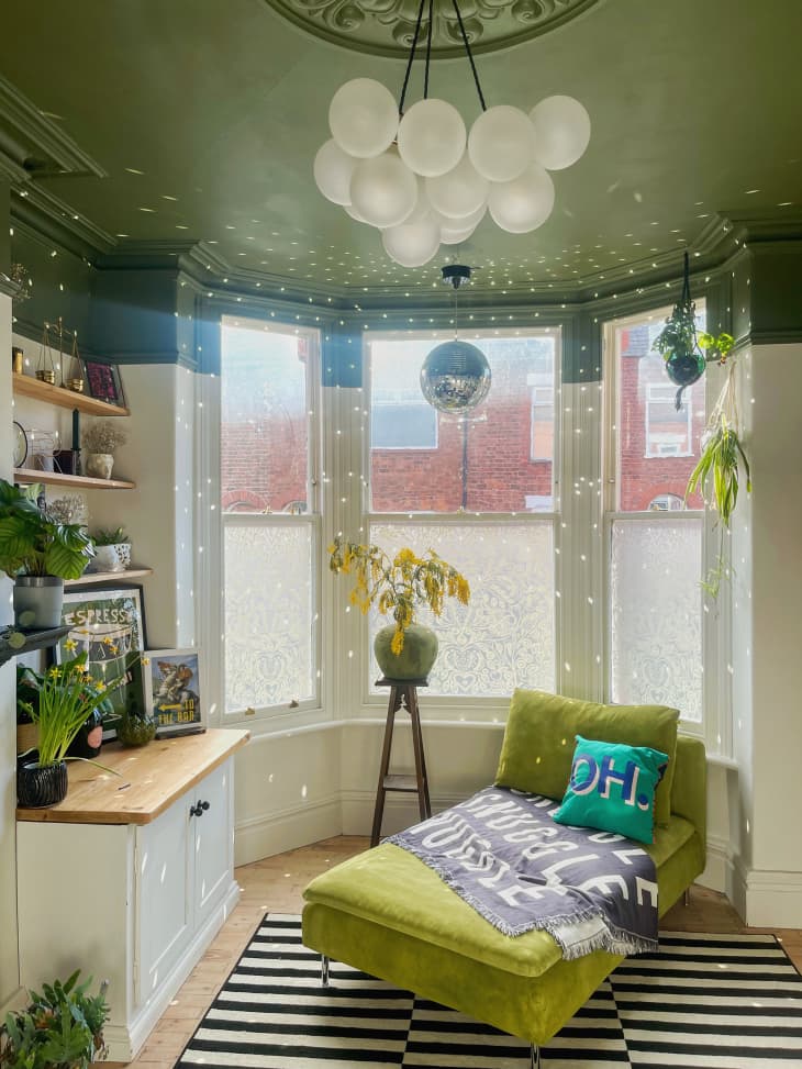 room with green ceiling, off white walls, black and white striped rug, other black and white accents, chandelier that looks like white balloons, green chaise