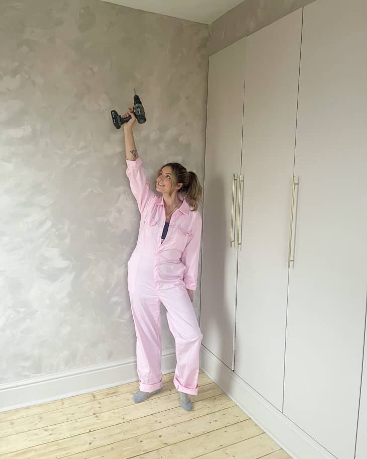 portrait of woman in pink coveralls holding up a drill