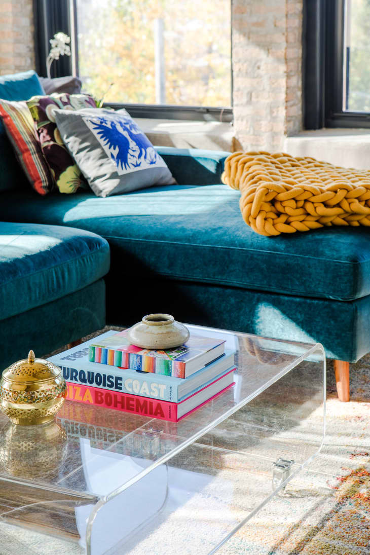 detail of living room with blue sofa, stack of coffee table books on coffee table, a couple decorative vessels