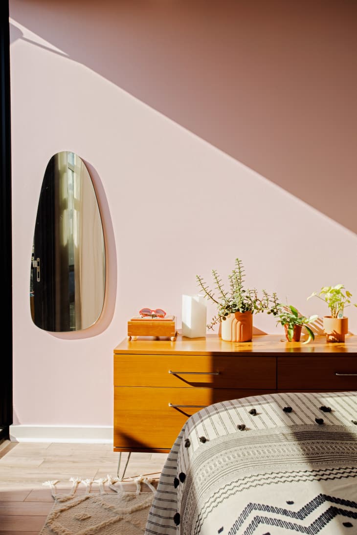 bedroom with pale pink wall, oblong-shaped mirror