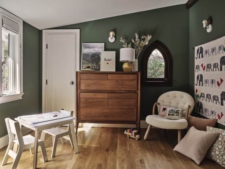 nursery with deep green walls, white trim, wood, warm colors and white accents