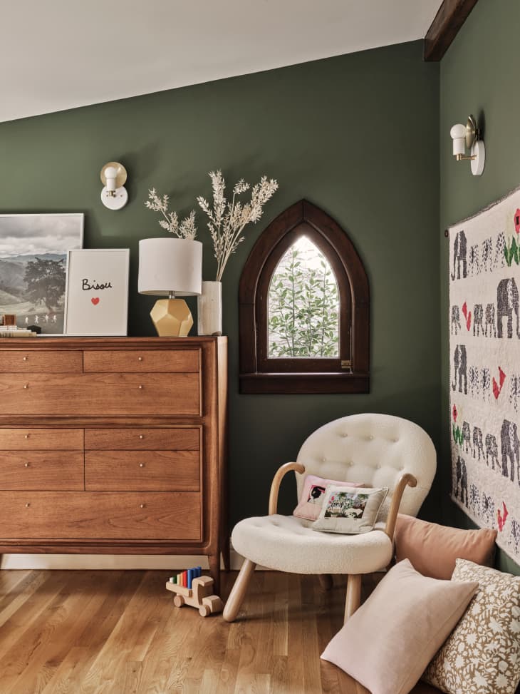 nursery with deep green walls, white trim, wood, warm colors and white accents