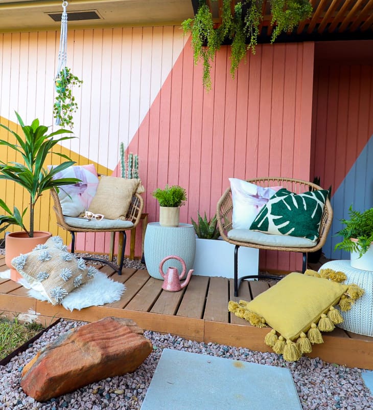 Colorful painted wooden wall in outdoor patio area with lots of seating and pillows.