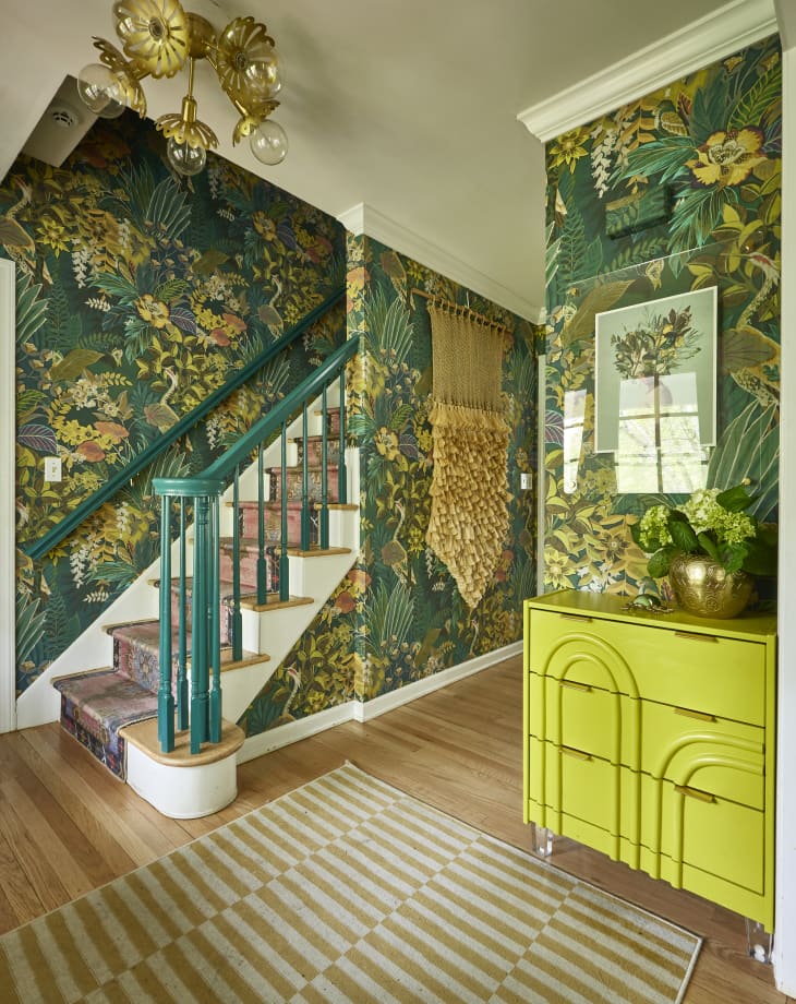 Green monochromatic entryway into home. Bold green botanical wall paper lines the walls.