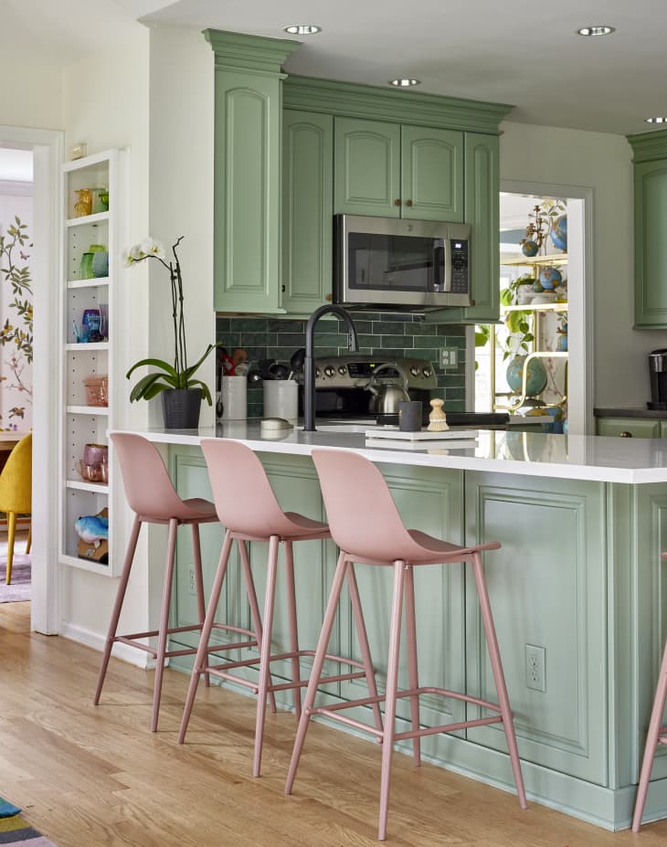 Pink stools line kitchen bar counter in pink and green kitchen.