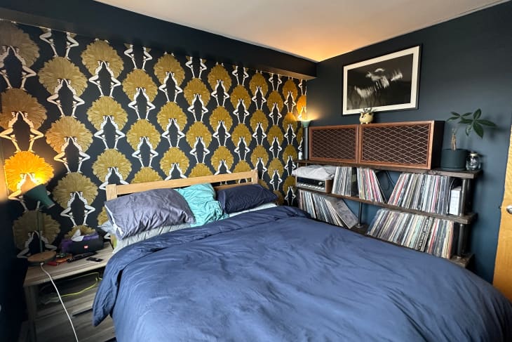 A blue bedroom with gold and blue wallpaper above the blue bed