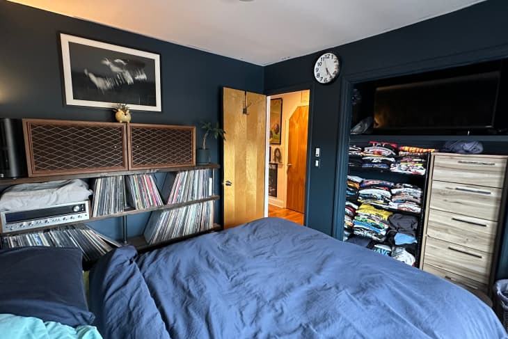 A blue bedroom with a record shelf and a t-shirt shelf