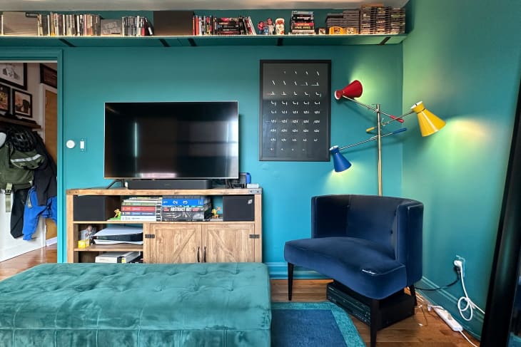 A blue-green living room with a blue velvet chairs sitting next to the tv