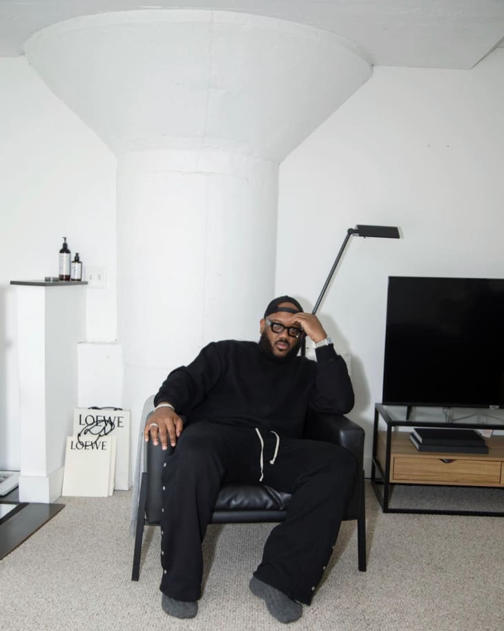 A man sitting in a white living room next to a tv stand