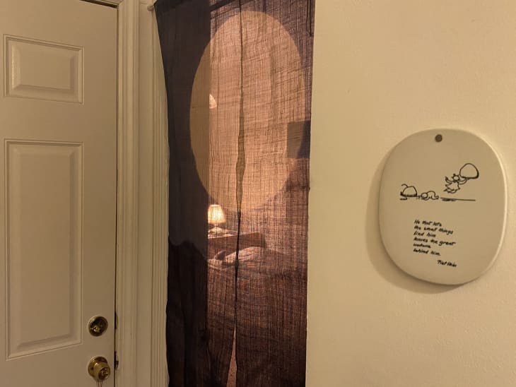 room with brown gauzy curtain as door, can see lit lamp