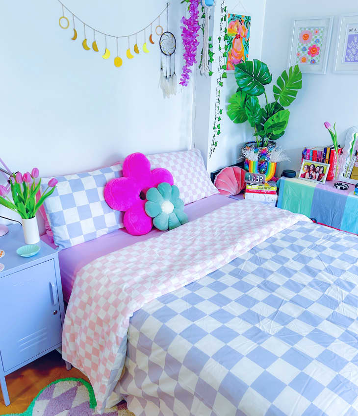 Checkerboard bedsheets in colorful bedroom with a mix of real and artificial plants.