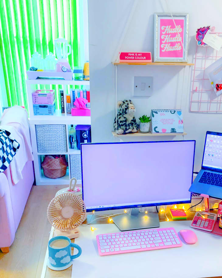Colorful work station with string lights and small shelves storing artwork in London apartment.